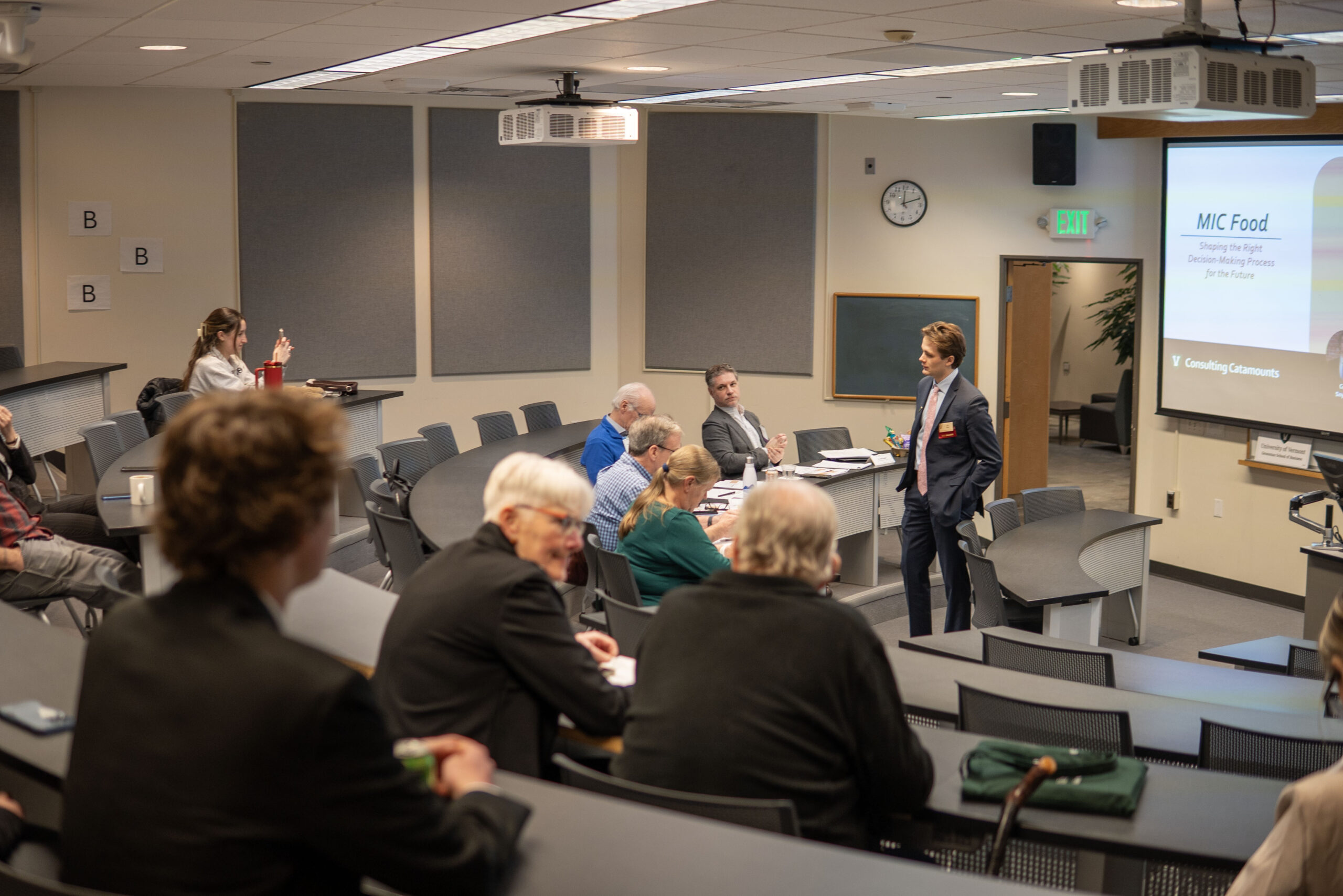 A student takes a moment to network with judges in an auditorium classroom