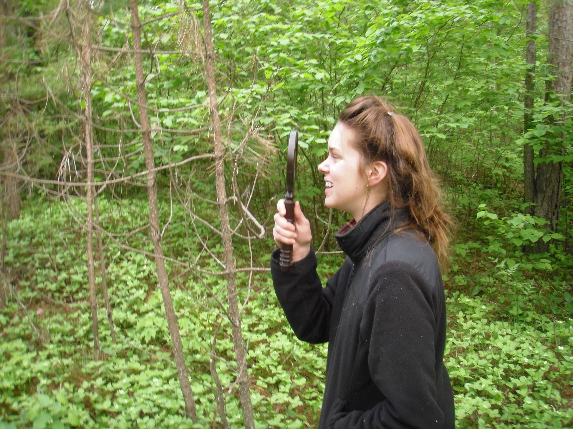 Young woman holding magnifying glass in woods