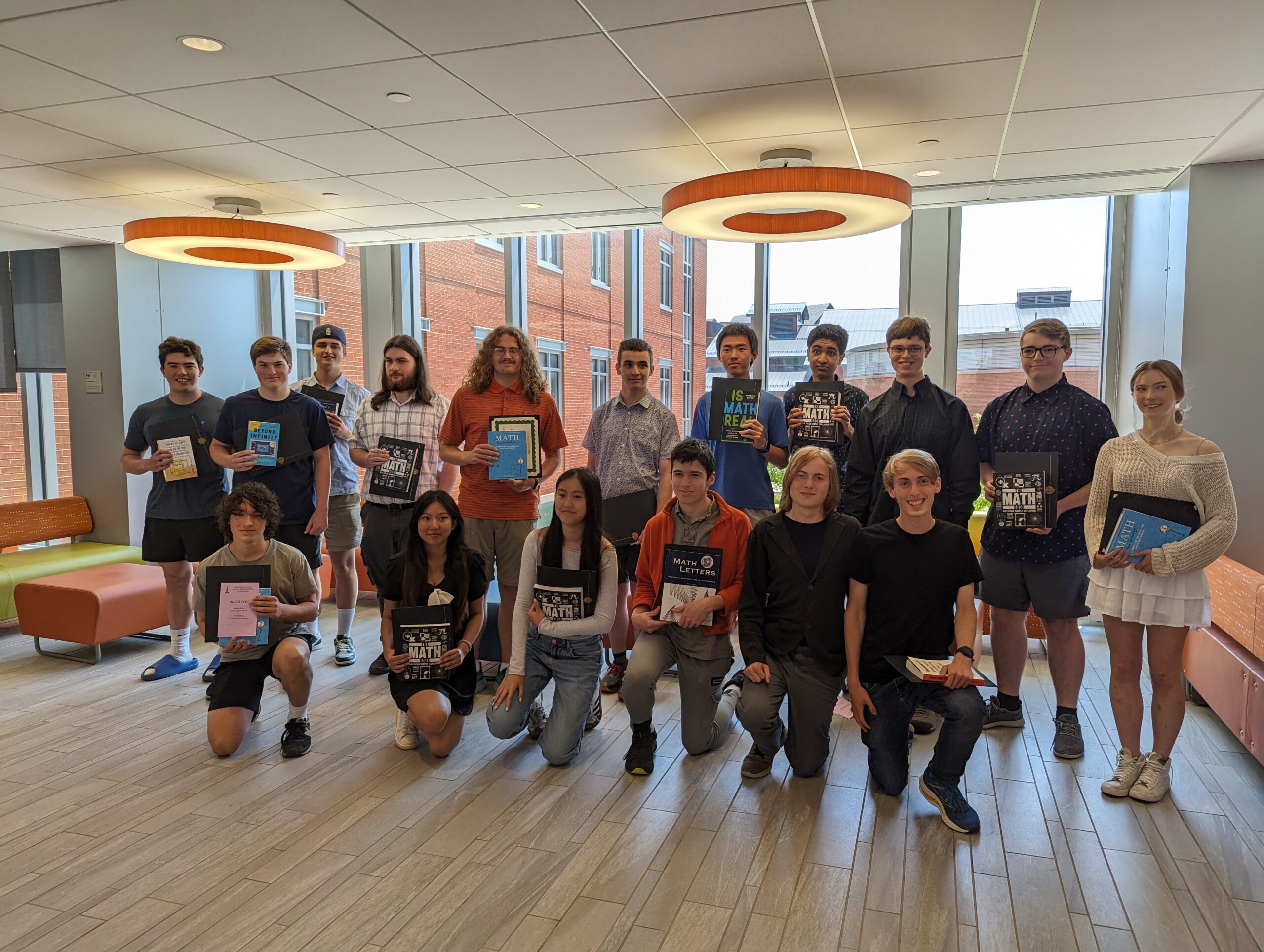 A group of high school students holding up their books and certificates received at Math Day