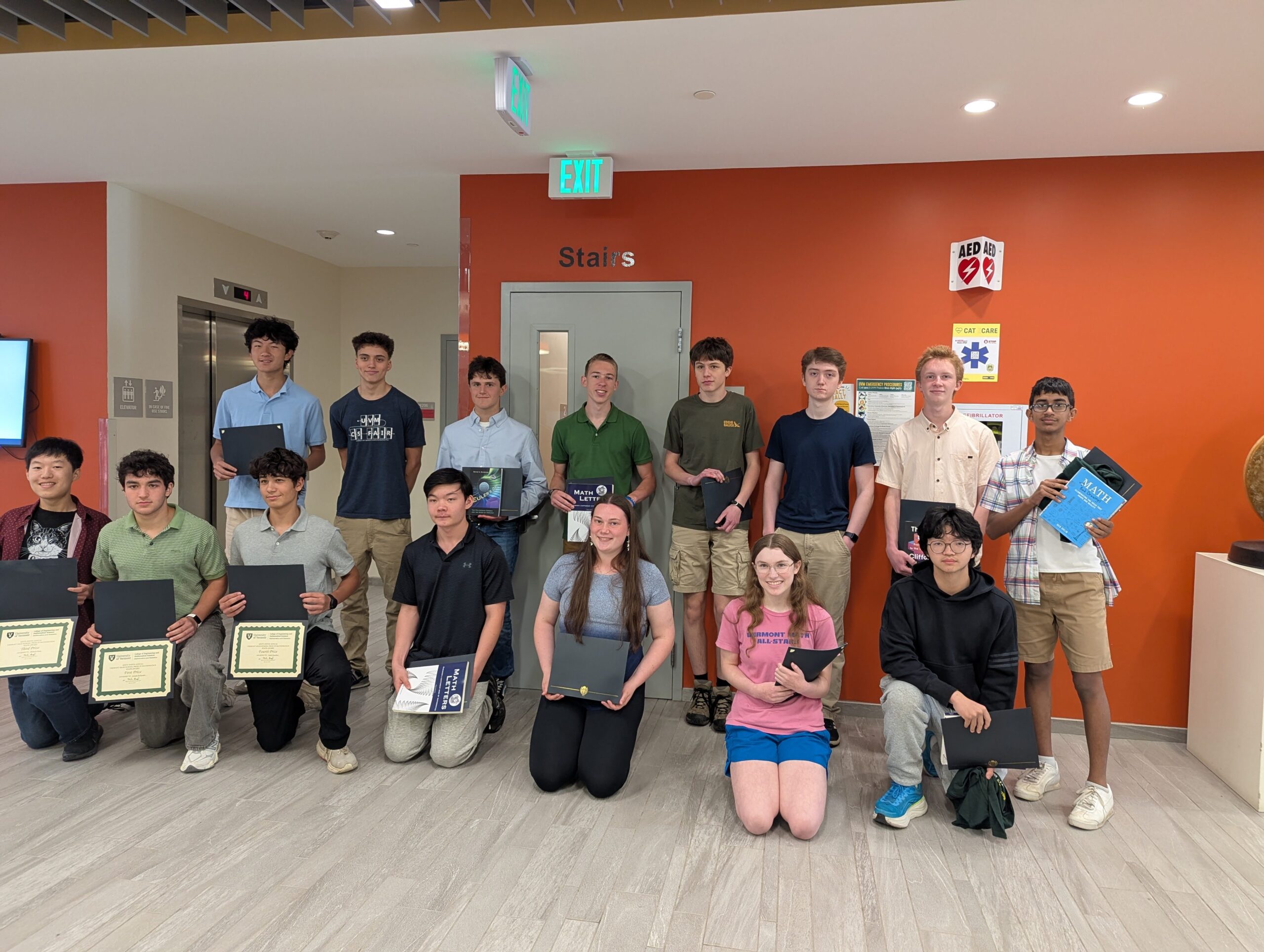 A group of students holding up their prize certificates and books.