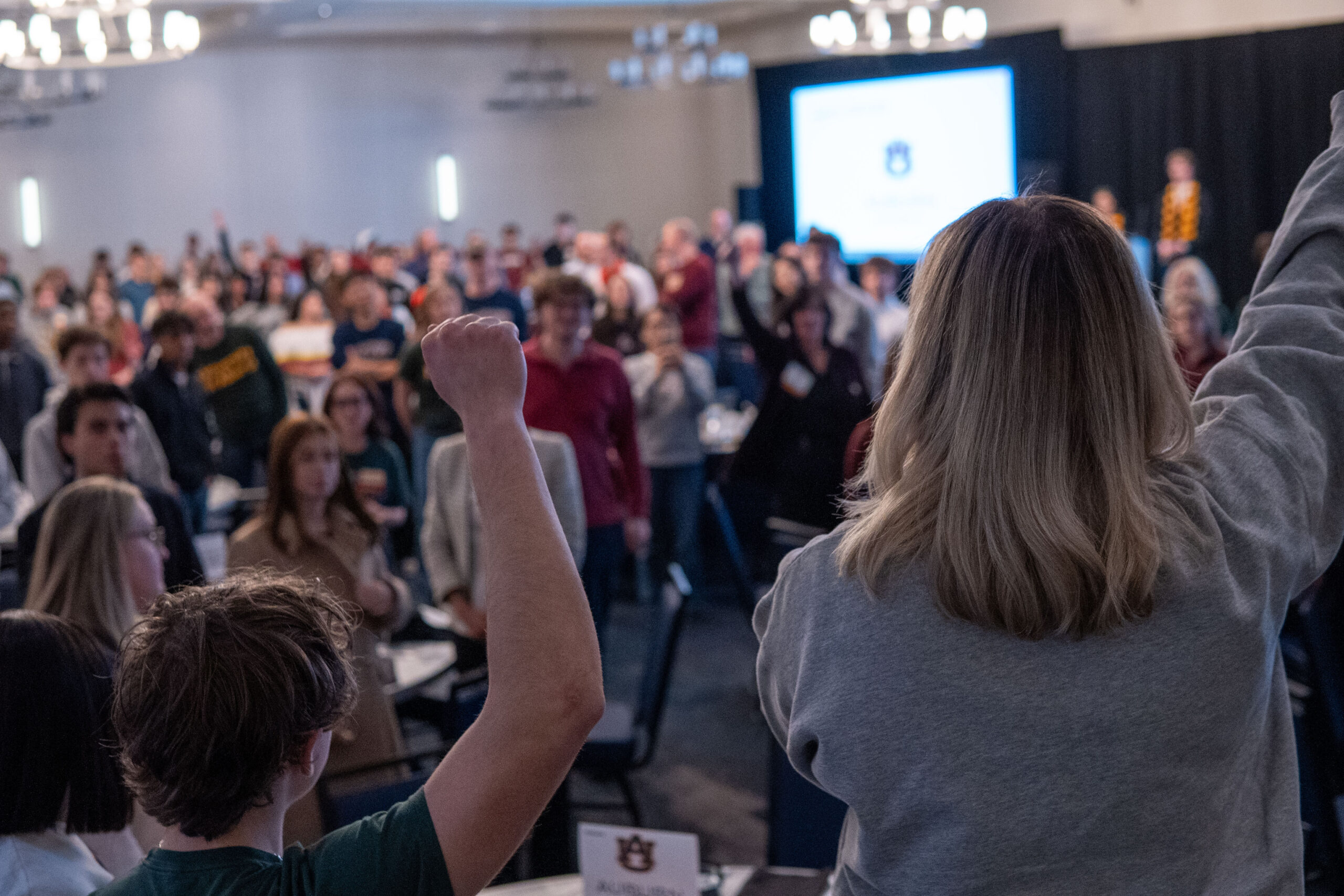 A crowd of students cheer in reaction with presenting students